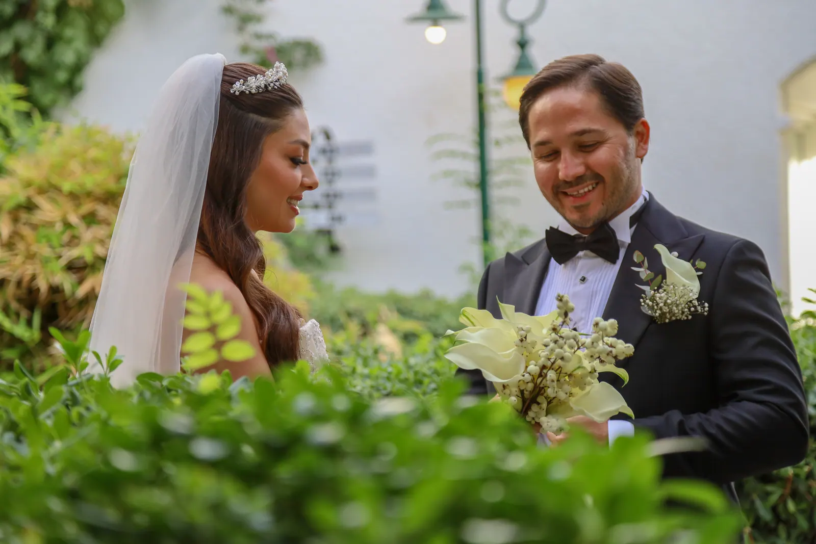 Bahçede kala zambağı buketiyle gülümseyen gelin ve damat