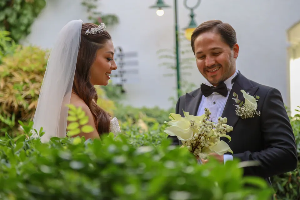 Bahçede kala zambağı buketiyle gülümseyen gelin ve damat