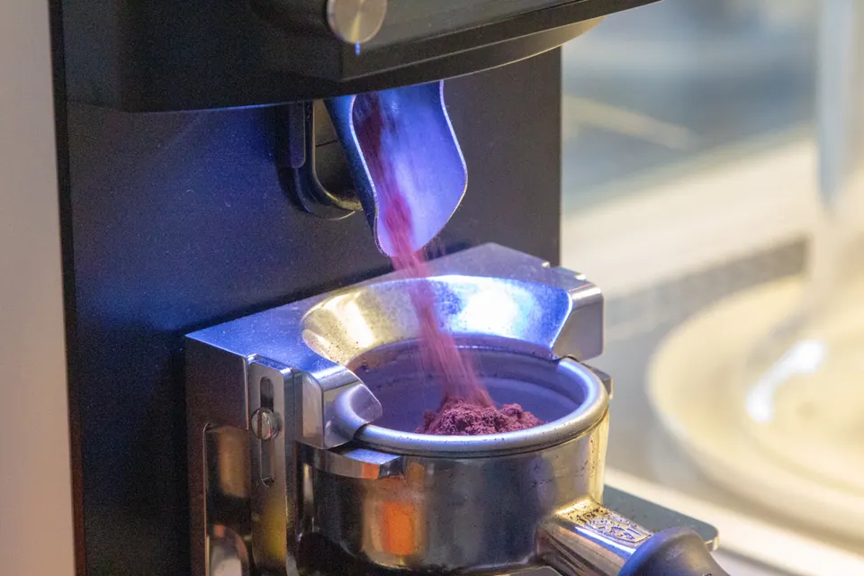 Espresso değirmeninden portafiltreye akan taze öğütülmüş kahve