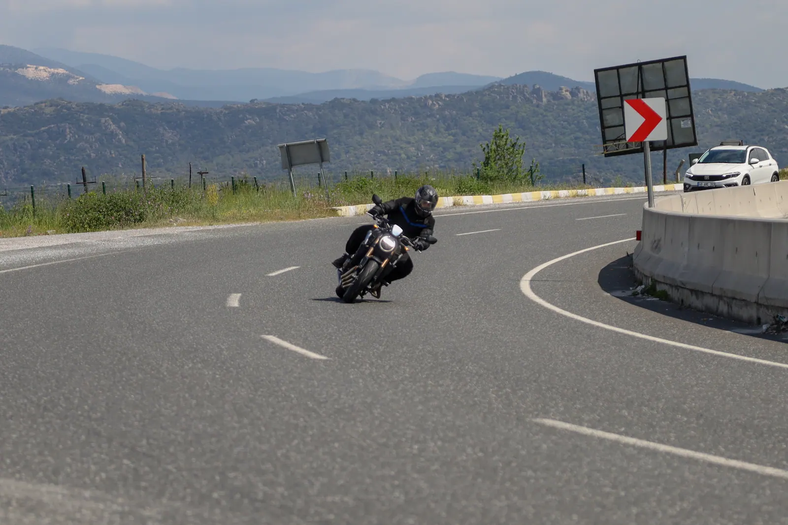 Dağ yolunda virajı yatarak dönen motosiklet sürücüsü