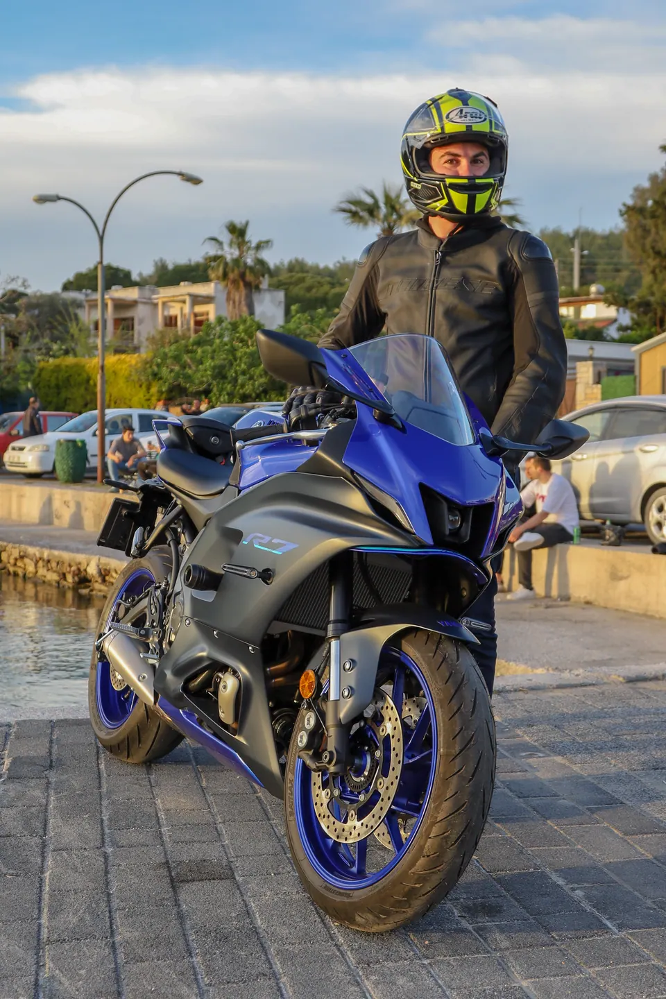 Sahil kenarında mavi spor motosikletiyle kasklı sürücü portresi