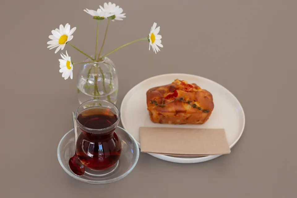 İnce belli bardakta çay, tuzlu kek ve papatyalar; kafe menü fotoğrafı